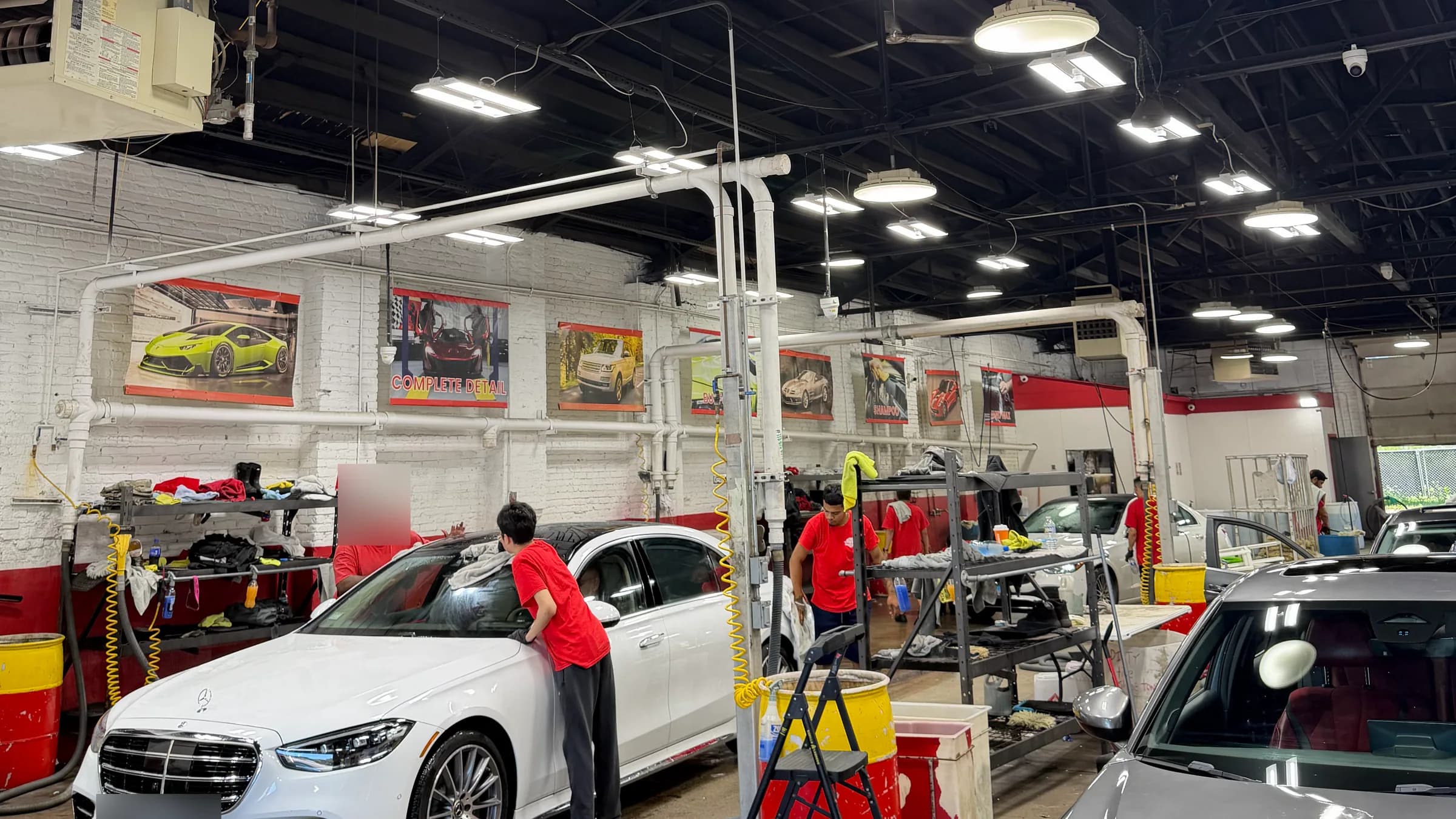 Cars being washed by hand inside the State Street Hand Car Wash service bay