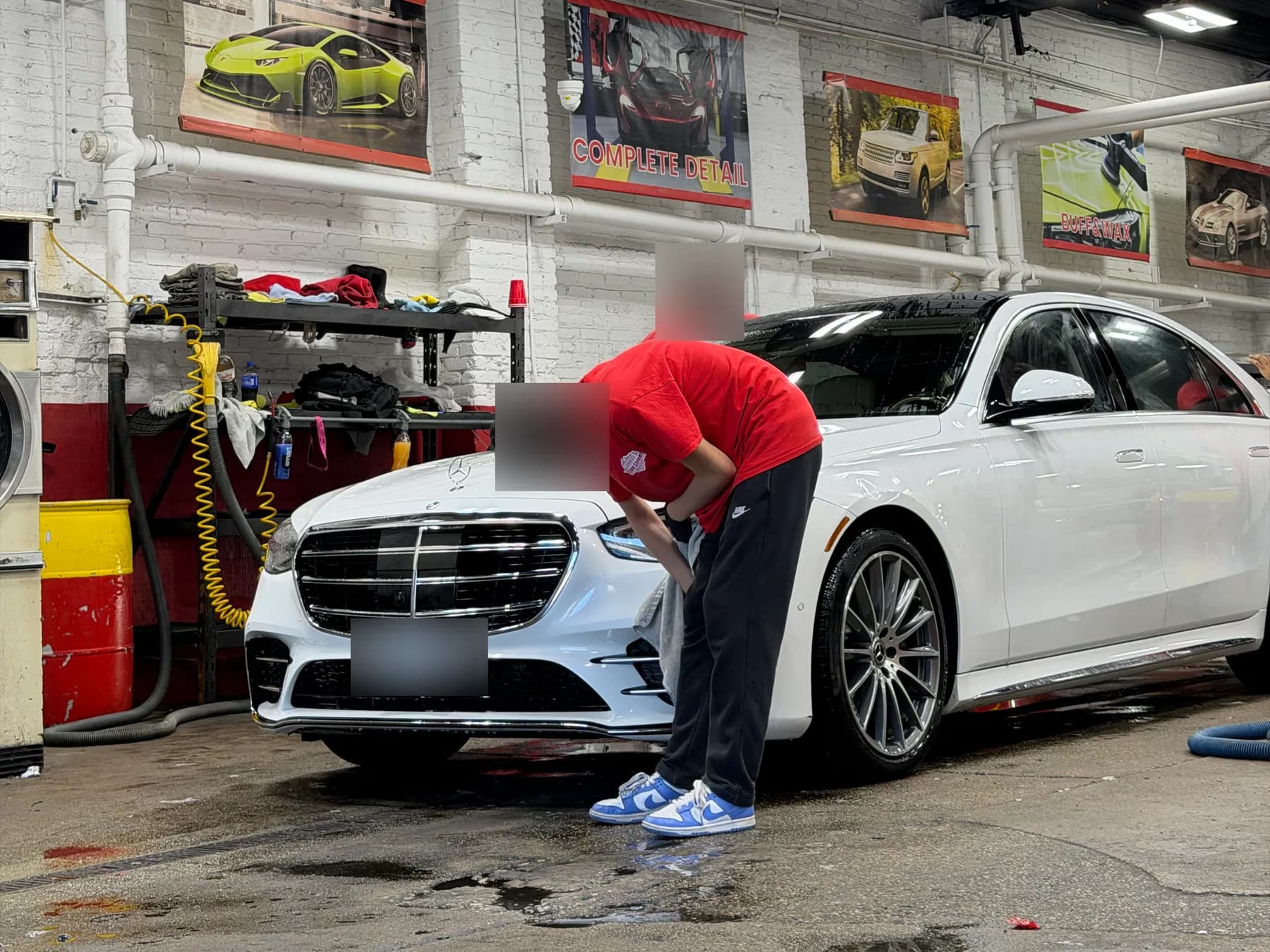 A team member hand washing the front of a white sedan in the service bay