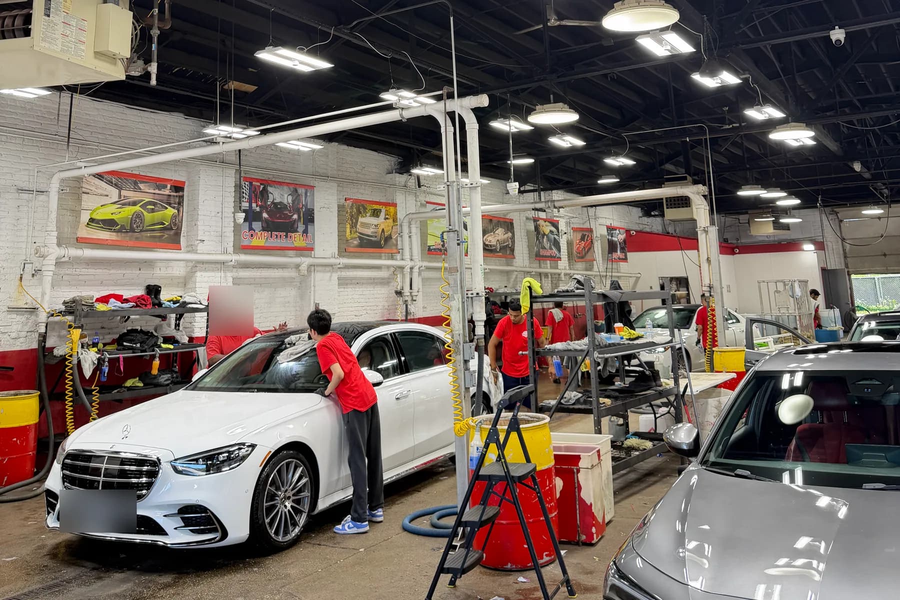 A team member washing a sedan by hand under the service bay lights