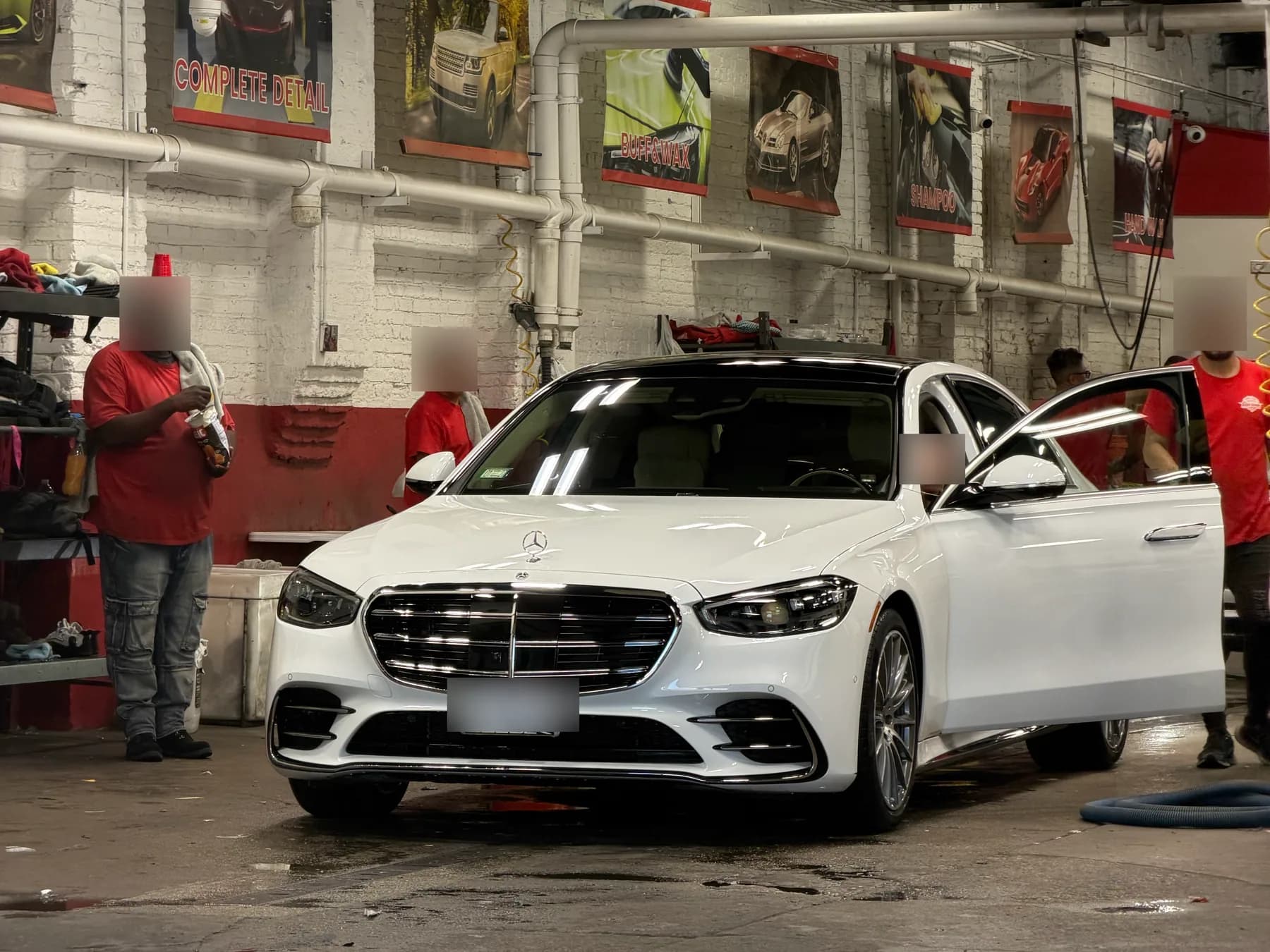 A sedan with its doors open in the wash bay while the cabin is cleaned